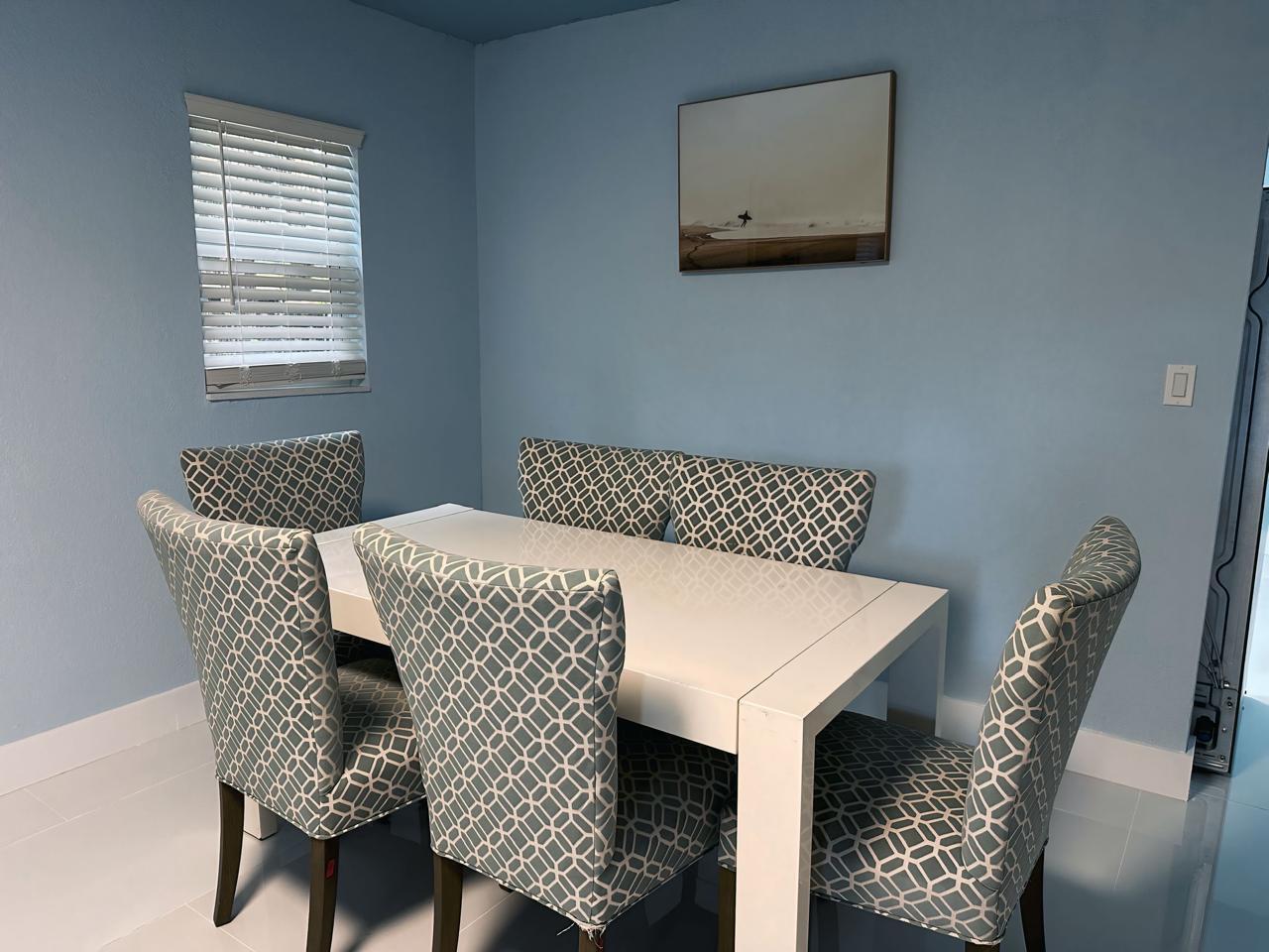A dining room with light blue walls, a white table, and four patterned upholstered chairs — 1702 NE 146th Street, Miami FL 33181, MIAMI, FL