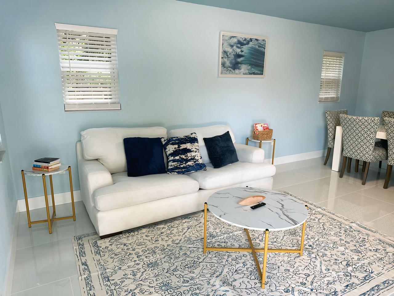 A living room features a white sofa, a marble-topped coffee table, and light blue walls — 1702 NE 146th Street, Miami FL 33181, MIAMI, FL