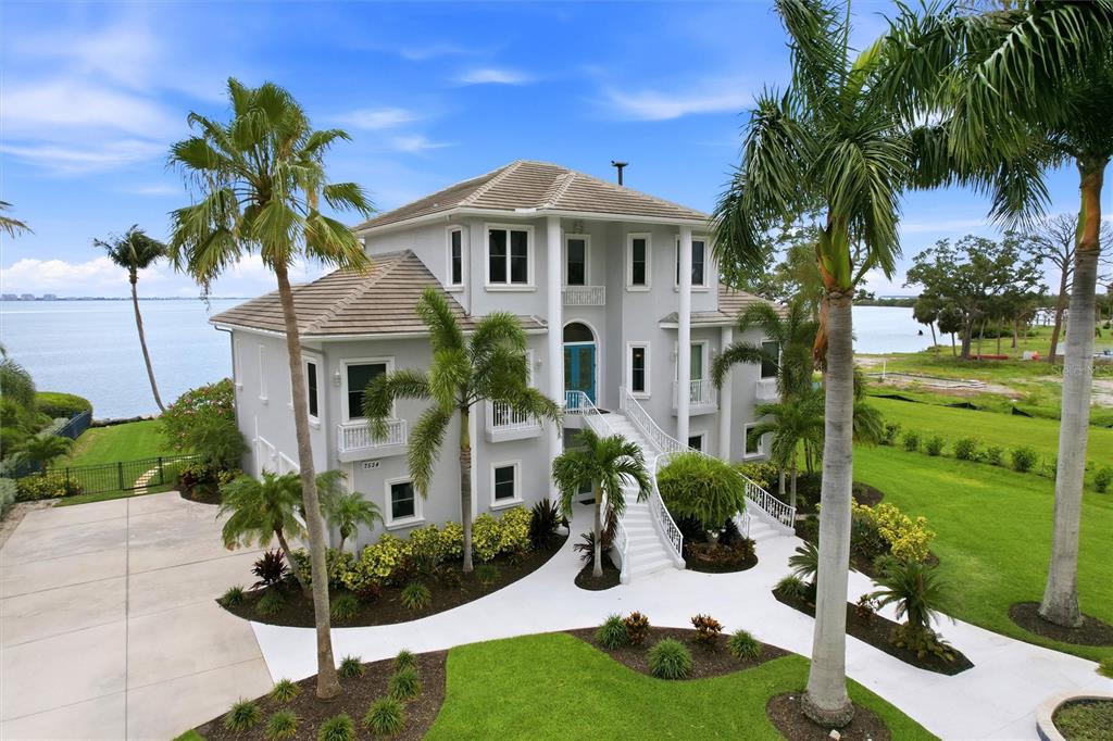 A large, multi-story gray house with a grand staircase sits on a waterfront lot — 7524 WESTMORELAND DRIVE, SARASOTA, FL