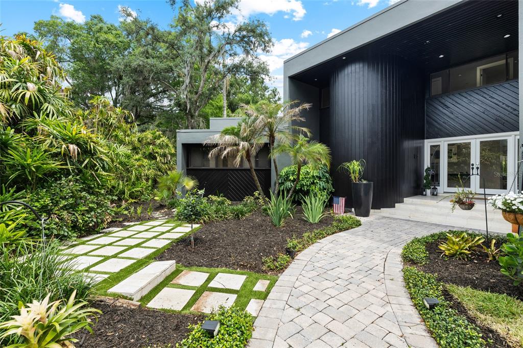 The exterior of a modern home features a black curved facade, stone walkway, and landscaping — 410 MONTROSE AVENUE, TEMPLE TERRACE, FL