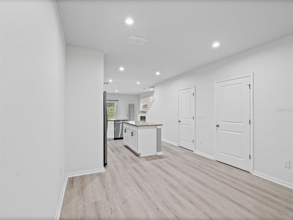 A bright kitchen features white cabinets, a central island, and light wood-look flooring — 3154 VICTORIA INLET DRIVE, HOLIDAY, FL