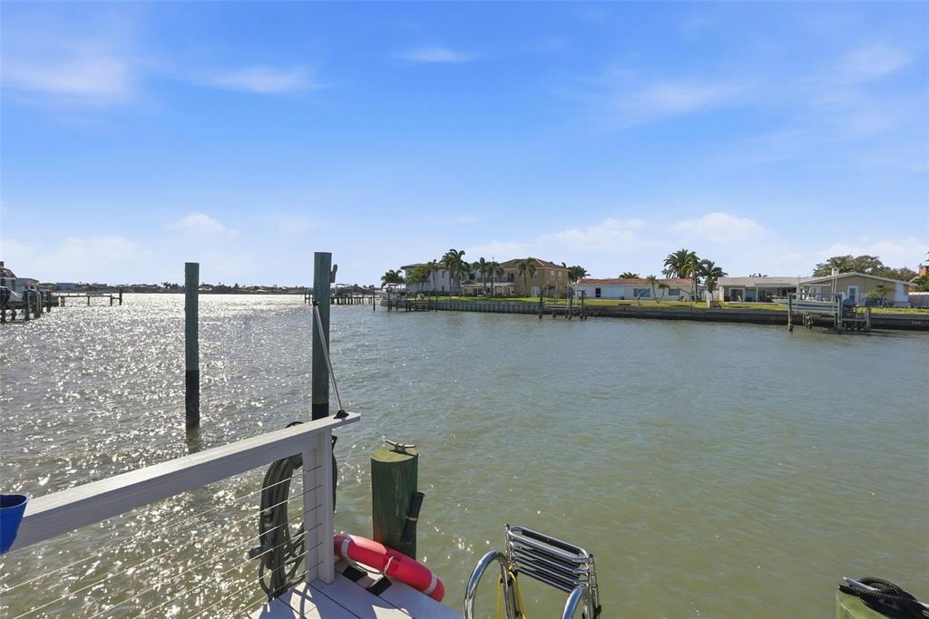A view from a wooden deck overlooking a canal with houses along the opposite shore — 573 BOCA CIEGA POINT BOULEVARD N, ST PETERSBURG, FL