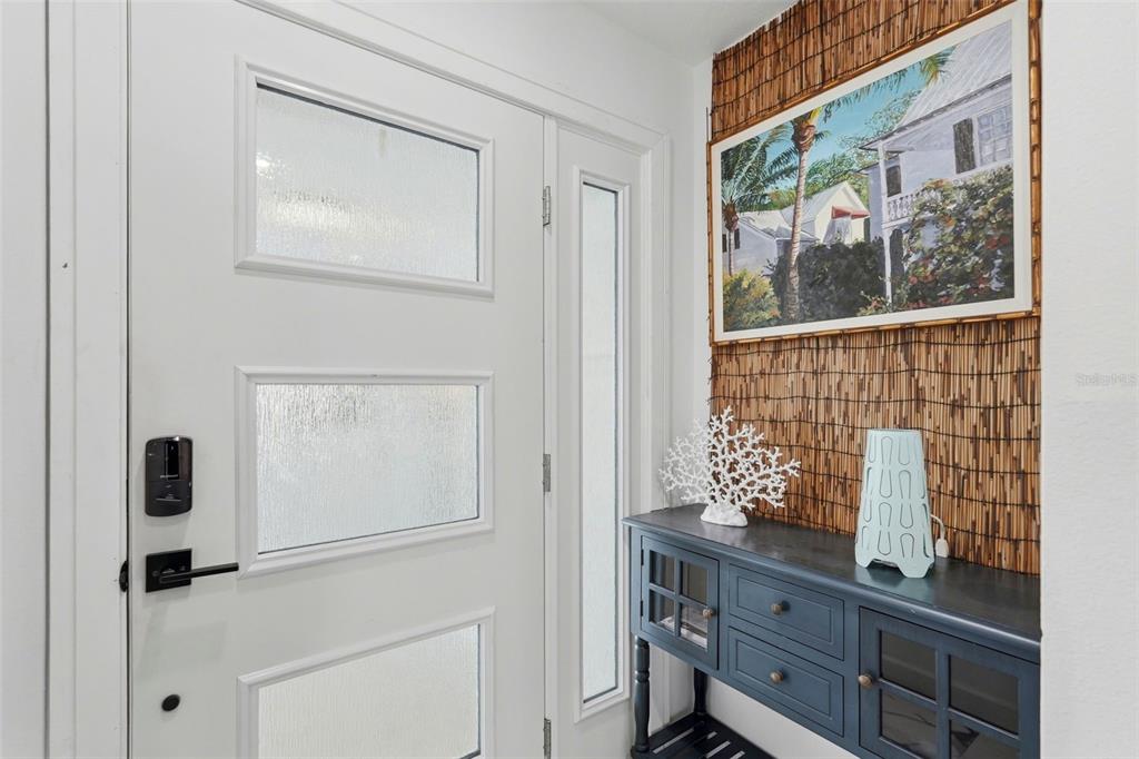 A white front door with frosted glass panels sits beside a console table and artwork — 573 BOCA CIEGA POINT BOULEVARD N, ST PETERSBURG, FL