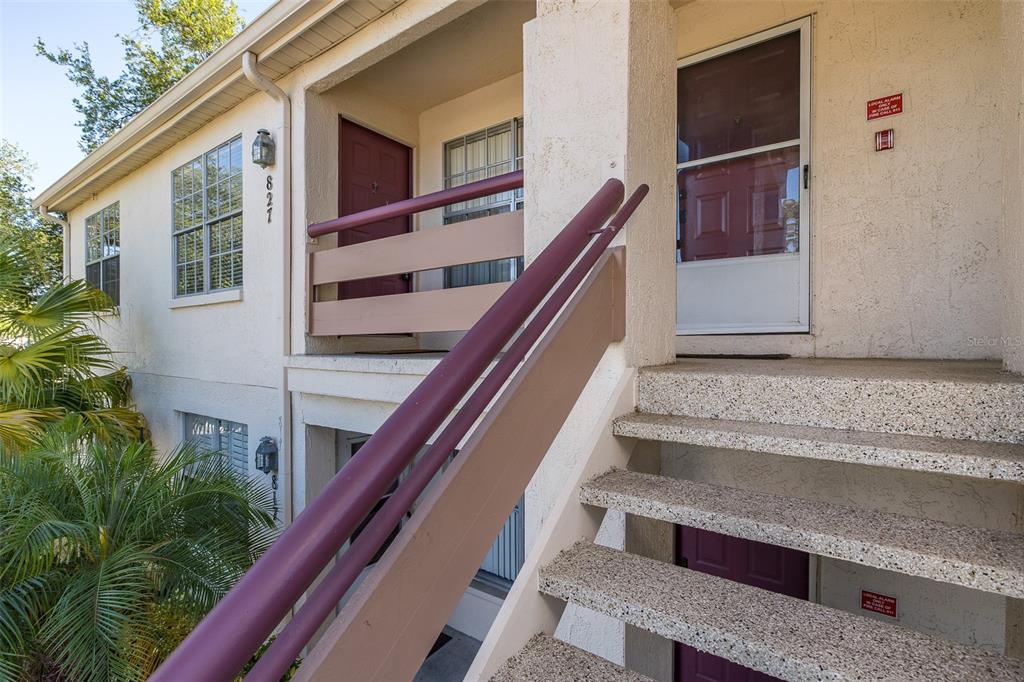 Exterior view of a two-story apartment building with concrete stairs and a metal railing — 7900 HARDWICK DRIVE UNIT 827, NEW PORT RICHEY, FL