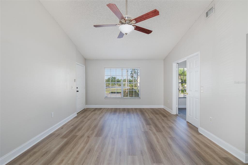 An empty room with light-colored walls, wood-look flooring, a vaulted ceiling, and a ceiling fan — 7900 HARDWICK DRIVE UNIT 827, NEW PORT RICHEY, FL