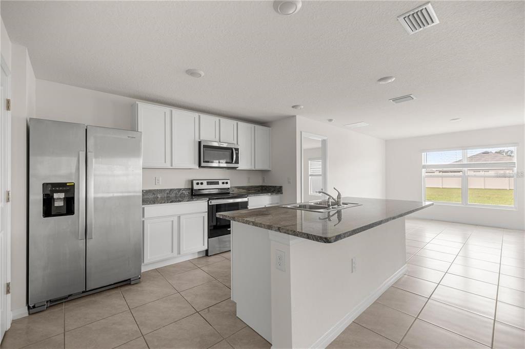 A kitchen with white cabinets, stainless steel appliances, and a granite-topped island — 8904 SW 50TH TERRACE, OCALA, FL
