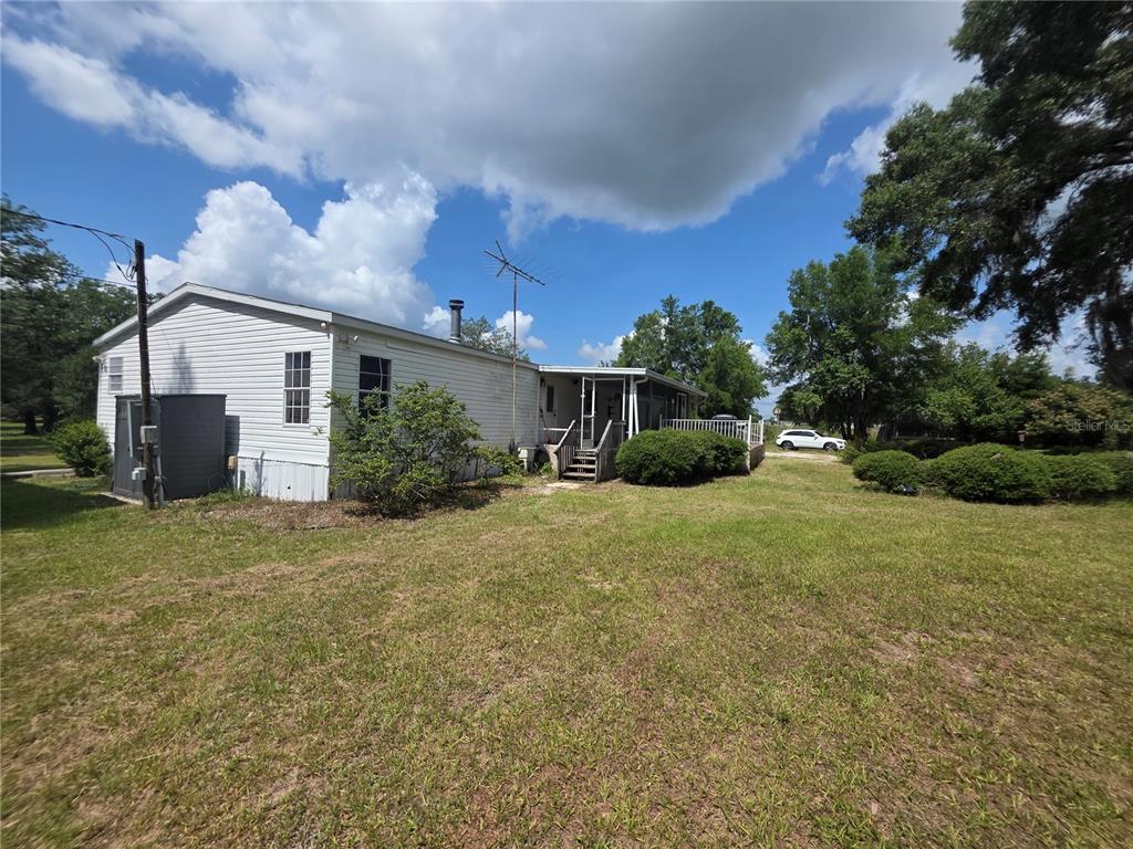A side view of a white mobile home with a small porch and grassy yard — 8095 SE 131ST PLACE, SUMMERFIELD, FL