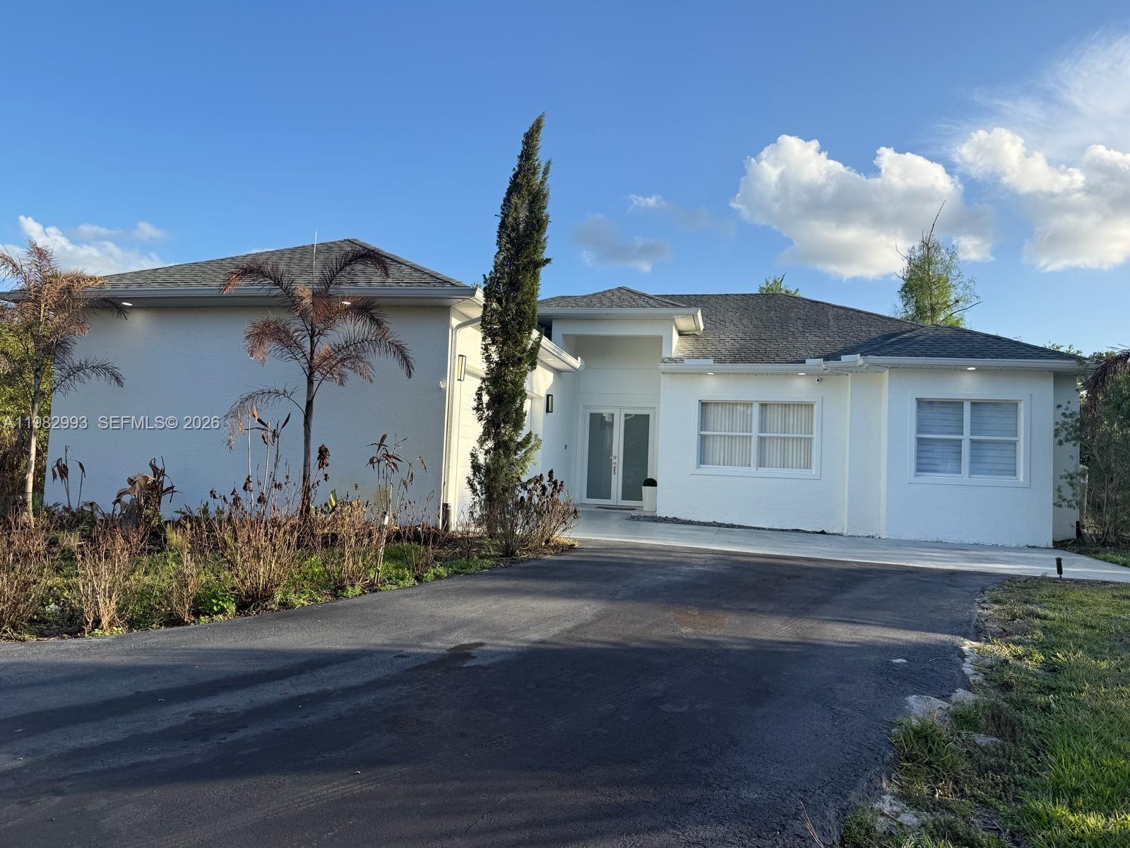 A white single-story house with a gray shingled roof and a paved driveway — 3646 28TH AVE SE, Naples FL 34117, NAPLES, FL