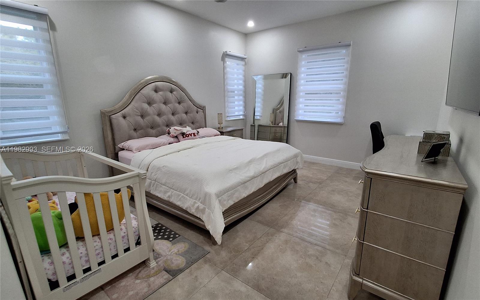 A bedroom features a tufted headboard, a white crib, and tile flooring — 3646 28TH AVE SE, Naples FL 34117, NAPLES, FL