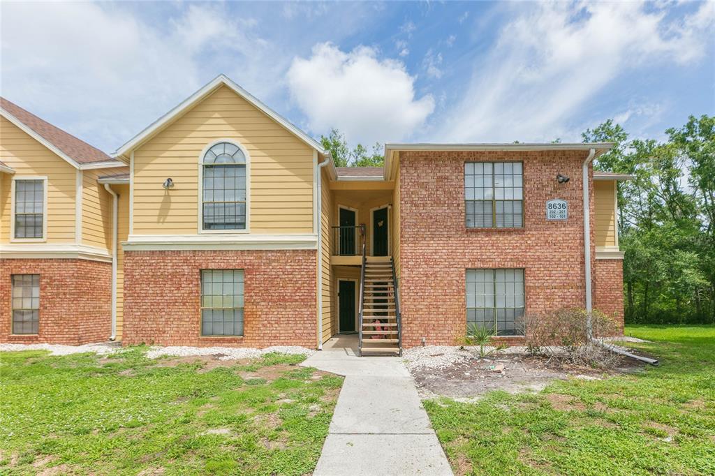 A two-story apartment building with brick and yellow siding features an exterior staircase and walkway — 8636 MALLARD RESERVE DRIVE UNIT 201, TAMPA, FL