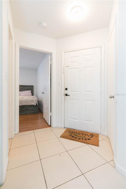 An entryway with tiled floors leads to a bedroom visible through an open doorway — 8636 MALLARD RESERVE DRIVE UNIT 201, TAMPA, FL