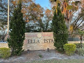 A stone monument sign for Bella Vista stands between two tall evergreen trees — 401 FOUNTAINHEAD CIRCLE UNIT 155, KISSIMMEE, FL