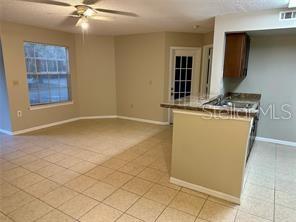 A living room with beige carpet and tile flooring features a kitchen island and window — 401 FOUNTAINHEAD CIRCLE UNIT 155, KISSIMMEE, FL