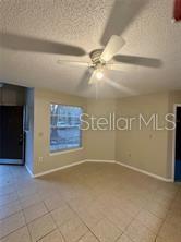 A room with beige tile flooring, a ceiling fan, and a window overlooking the outdoors — 401 FOUNTAINHEAD CIRCLE UNIT 155, KISSIMMEE, FL