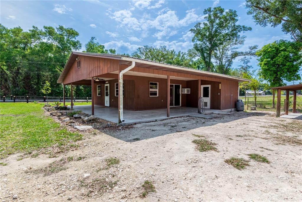 A brown wooden house with a large covered concrete porch sits on a gravel lot — 6150 NW COUNTY ROAD 345, CHIEFLAND, FL
