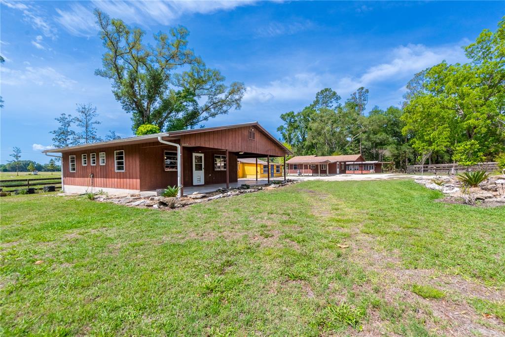 A brown wooden building with a covered porch stands on a grassy rural property — 6150 NW COUNTY ROAD 345, CHIEFLAND, FL