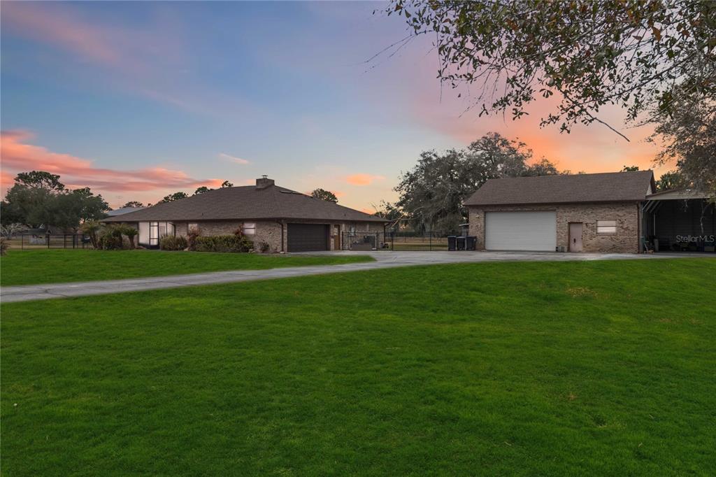 A brick house and a detached garage sit on a large lawn at sunset — 18711 NORTHCLIFF STREET, ORLANDO, FL