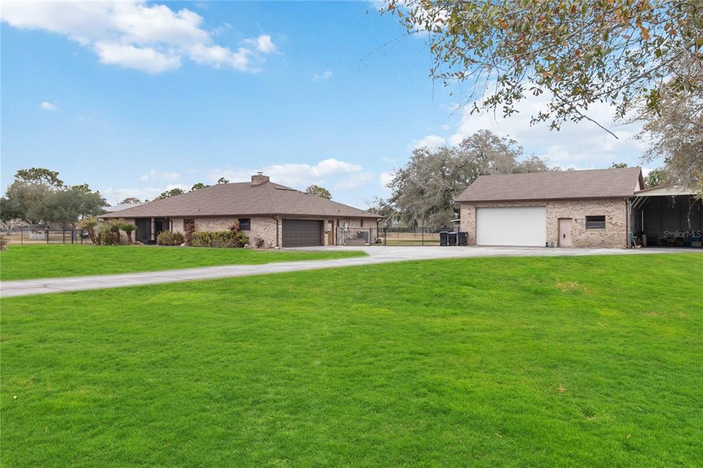 A brick house and a detached garage sit on a large, grassy lot — 18711 NORTHCLIFF STREET, ORLANDO, FL