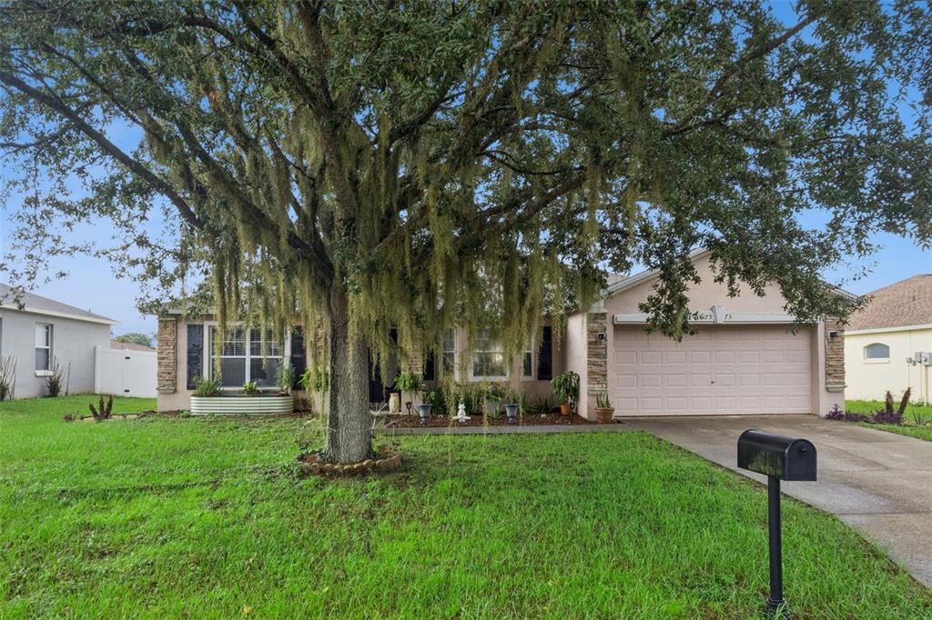 A single-story house with a stone-accented entryway, a concrete walkway, and a green metal planter — 7973 OAK RUN CIRCLE, LAKELAND, FL