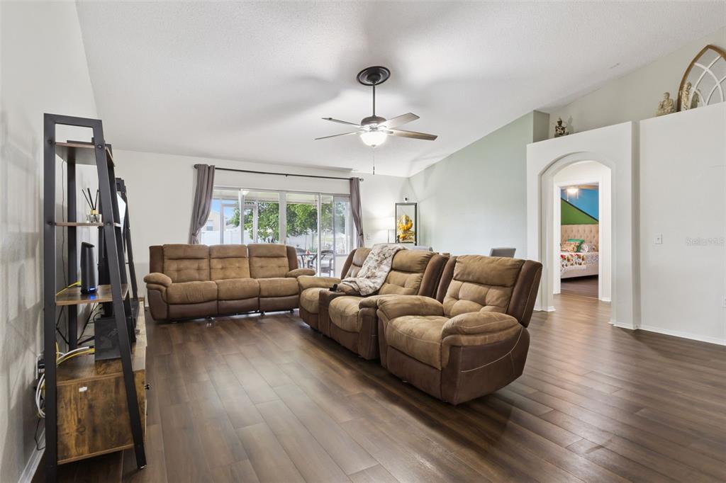 A living room features brown reclining sofas, wood-look flooring, and a ceiling fan — 7973 OAK RUN CIRCLE, LAKELAND, FL