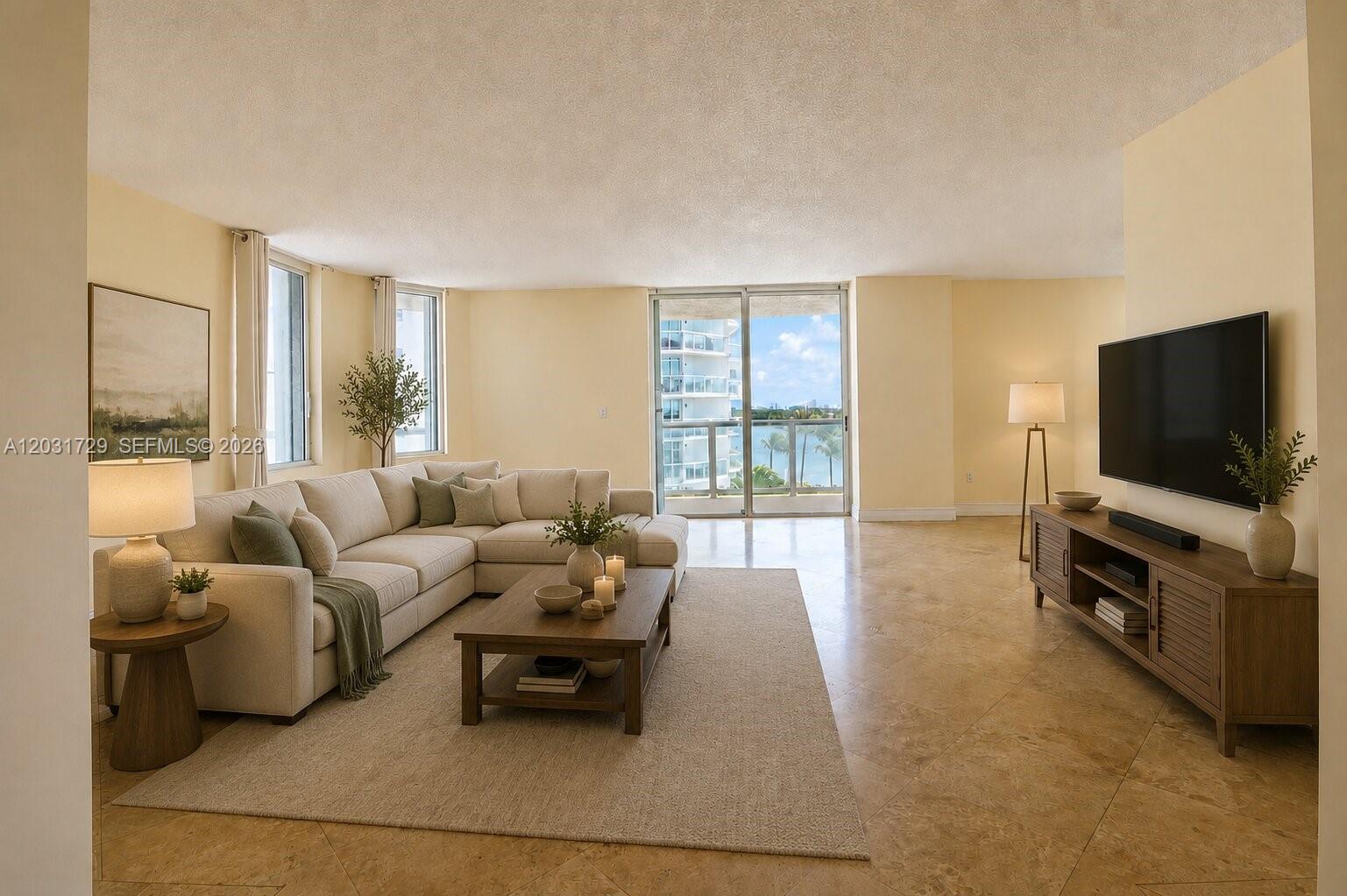 A living room features a beige sectional sofa, a wooden coffee table, and a television — 5900 Collins Ave # 601, Miami Beach FL 33140, MIAMI BEACH, FL