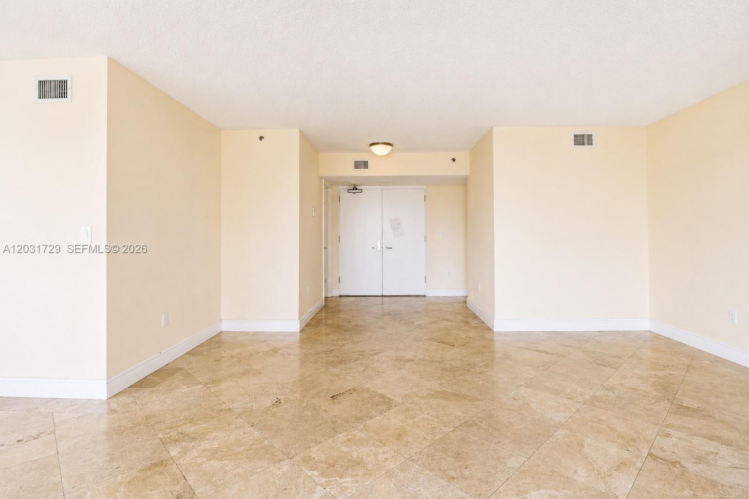 An empty room features beige walls, light-colored tile flooring, and a double-door entryway — 5900 Collins Ave # 601, Miami Beach FL 33140, MIAMI BEACH, FL