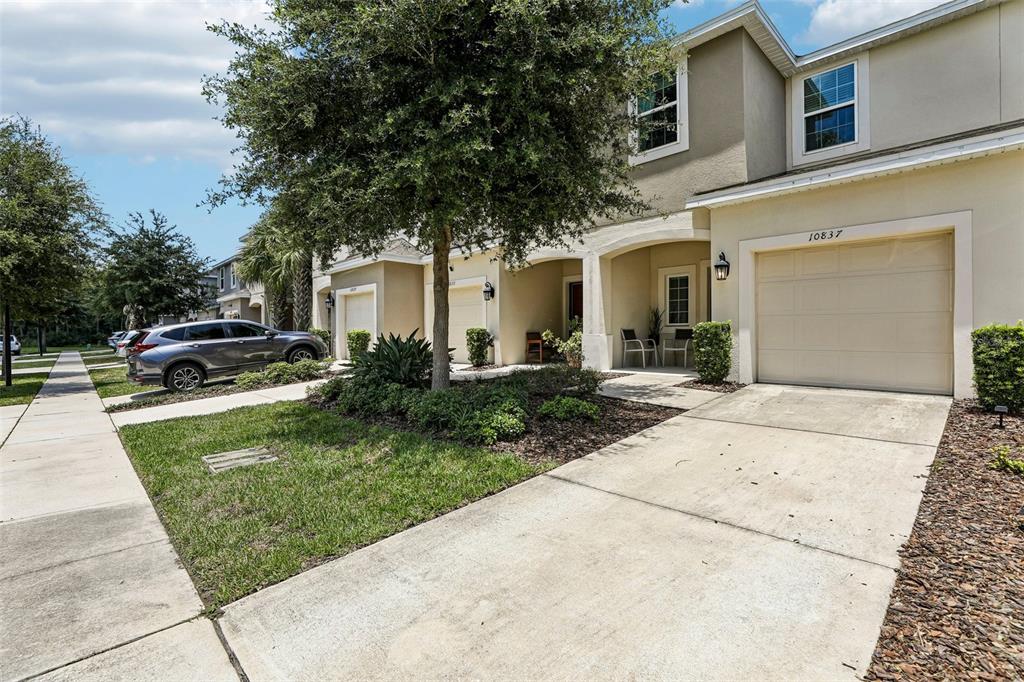 A two-story townhouse with a beige stucco exterior, a single-car garage, and a front walkway — 10837 WYNE TREE COURT, ORLANDO, FL