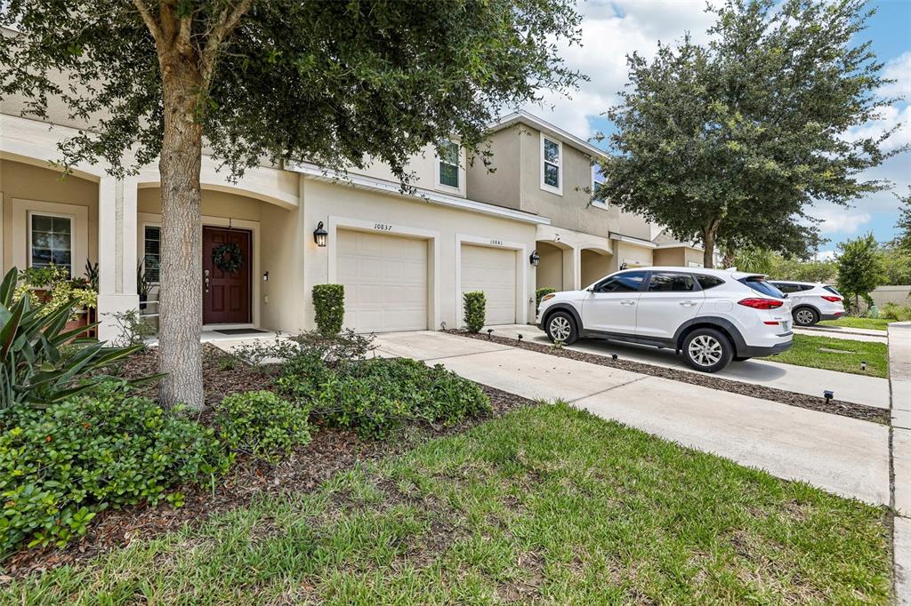 A row of townhomes features beige stucco exteriors, attached garages, and a white SUV parked outside — 10837 WYNE TREE COURT, ORLANDO, FL