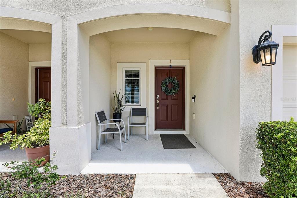 A covered entryway features a red front door, two chairs, and a potted plant — 10837 WYNE TREE COURT, ORLANDO, FL