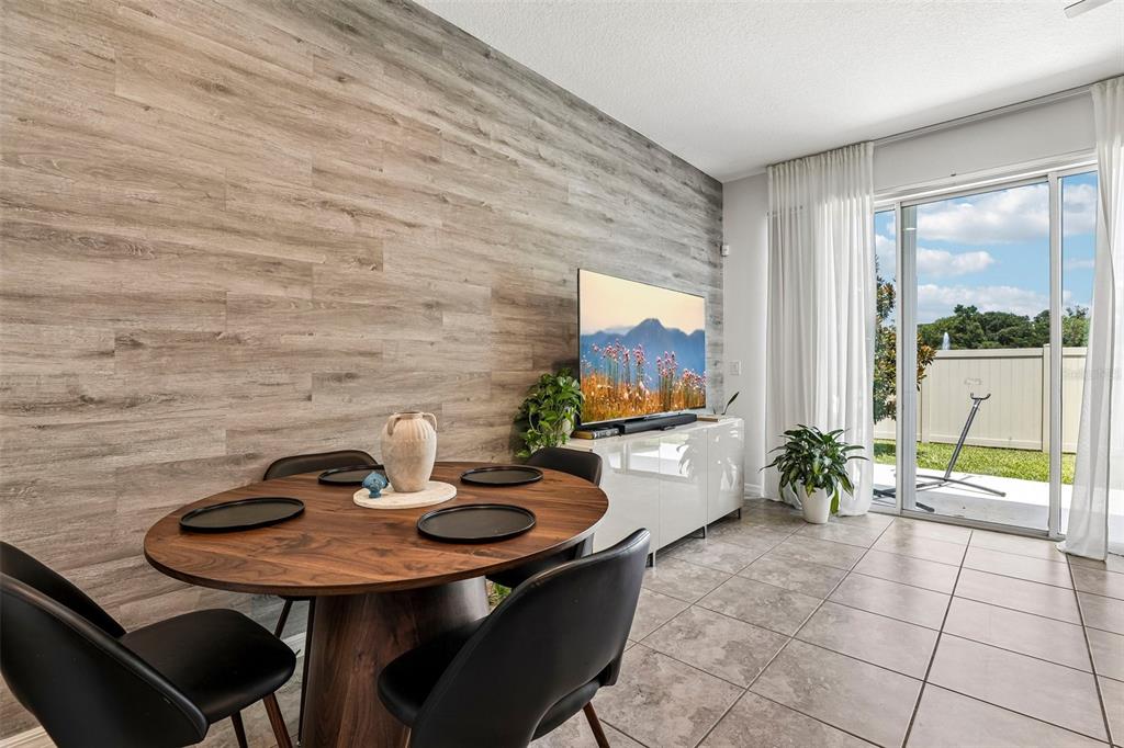 A dining area features a wood-look accent wall, a round table, and sliding glass doors — 10837 WYNE TREE COURT, ORLANDO, FL