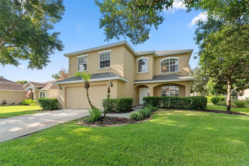 A two-story tan house with a two-car garage and a landscaped front yard — 315 SUNCREST COURT, OVIEDO, FL