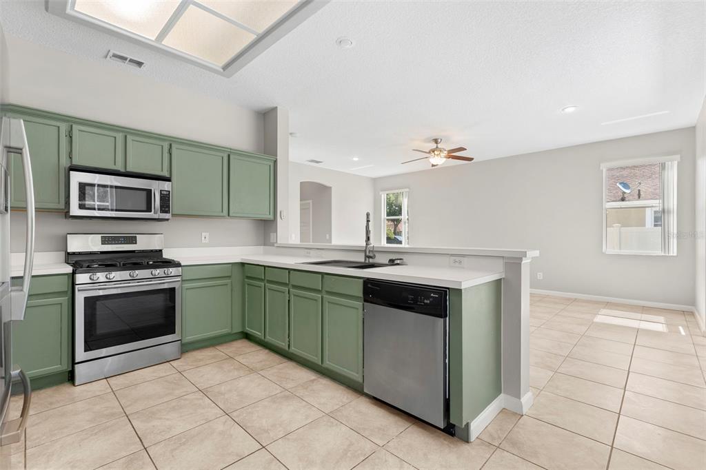 A kitchen with sage green cabinets, stainless steel appliances, and tile flooring — 315 SUNCREST COURT, OVIEDO, FL