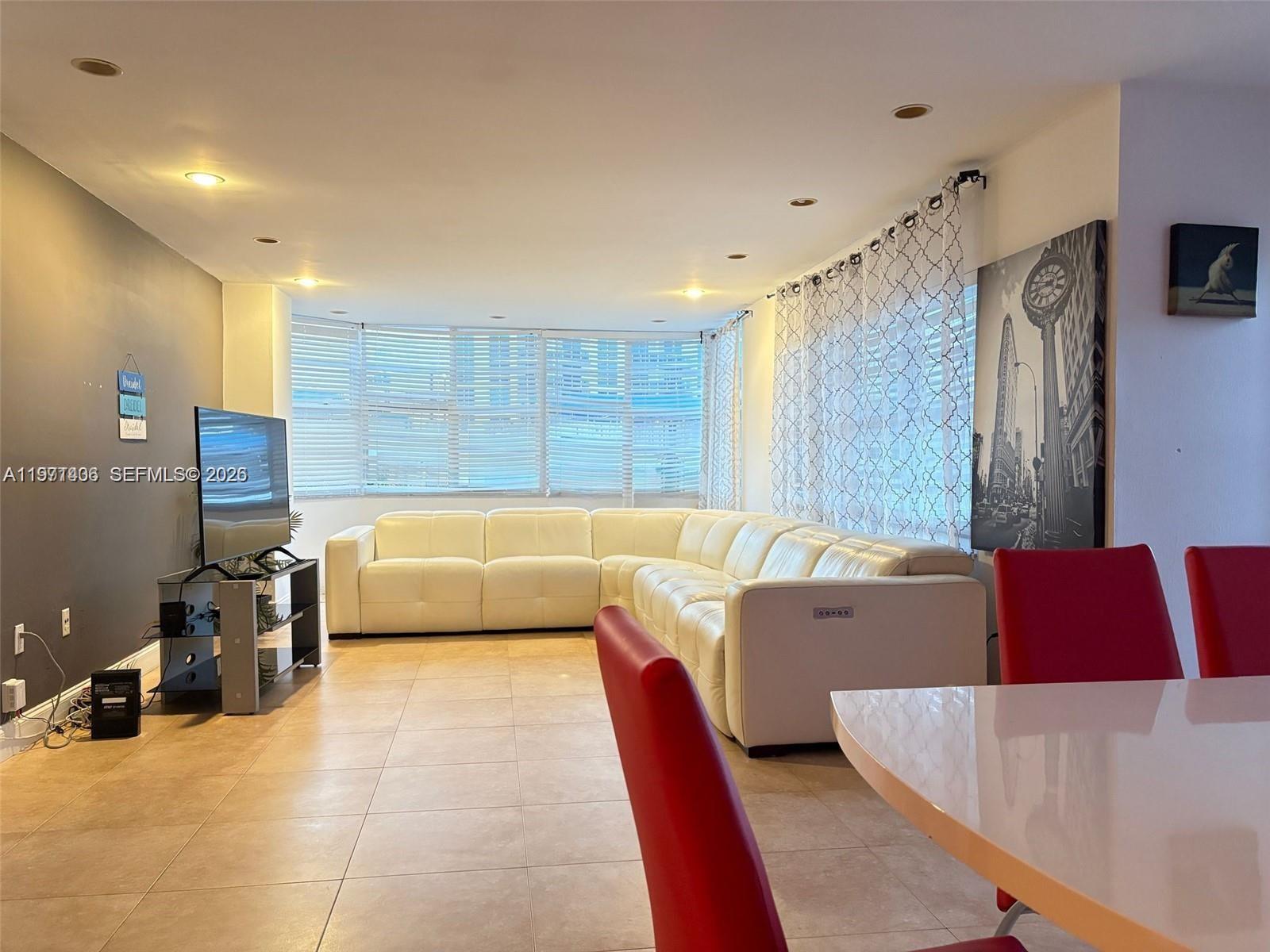 A living room features a white sectional sofa, tile flooring, and a large window wall — 1965 S Ocean Dr # 2F, Hallandale Beach FL 33009, HALLANDALE BEACH, FL