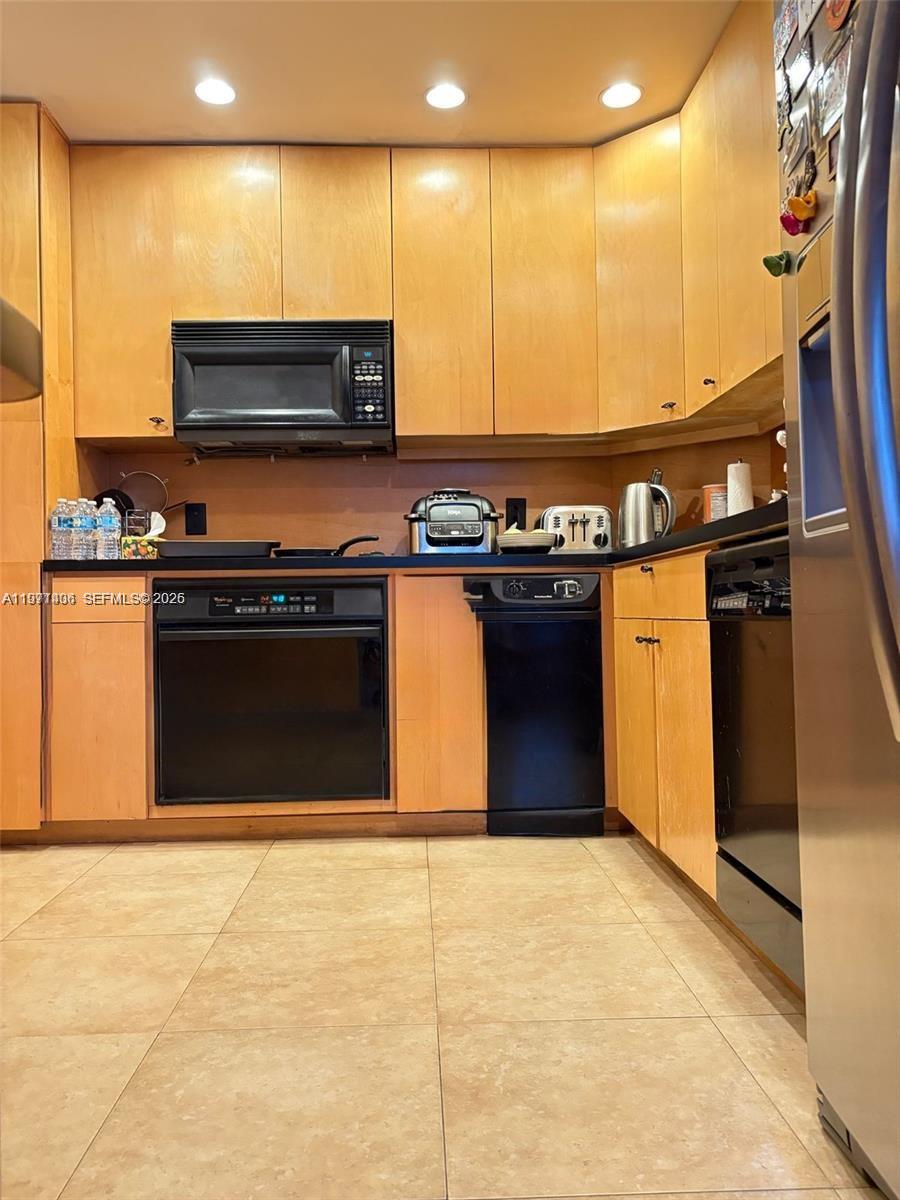 A kitchen features light wood cabinets, black appliances, and light-colored tile flooring — 1965 S Ocean Dr # 2F, Hallandale Beach FL 33009, HALLANDALE BEACH, FL