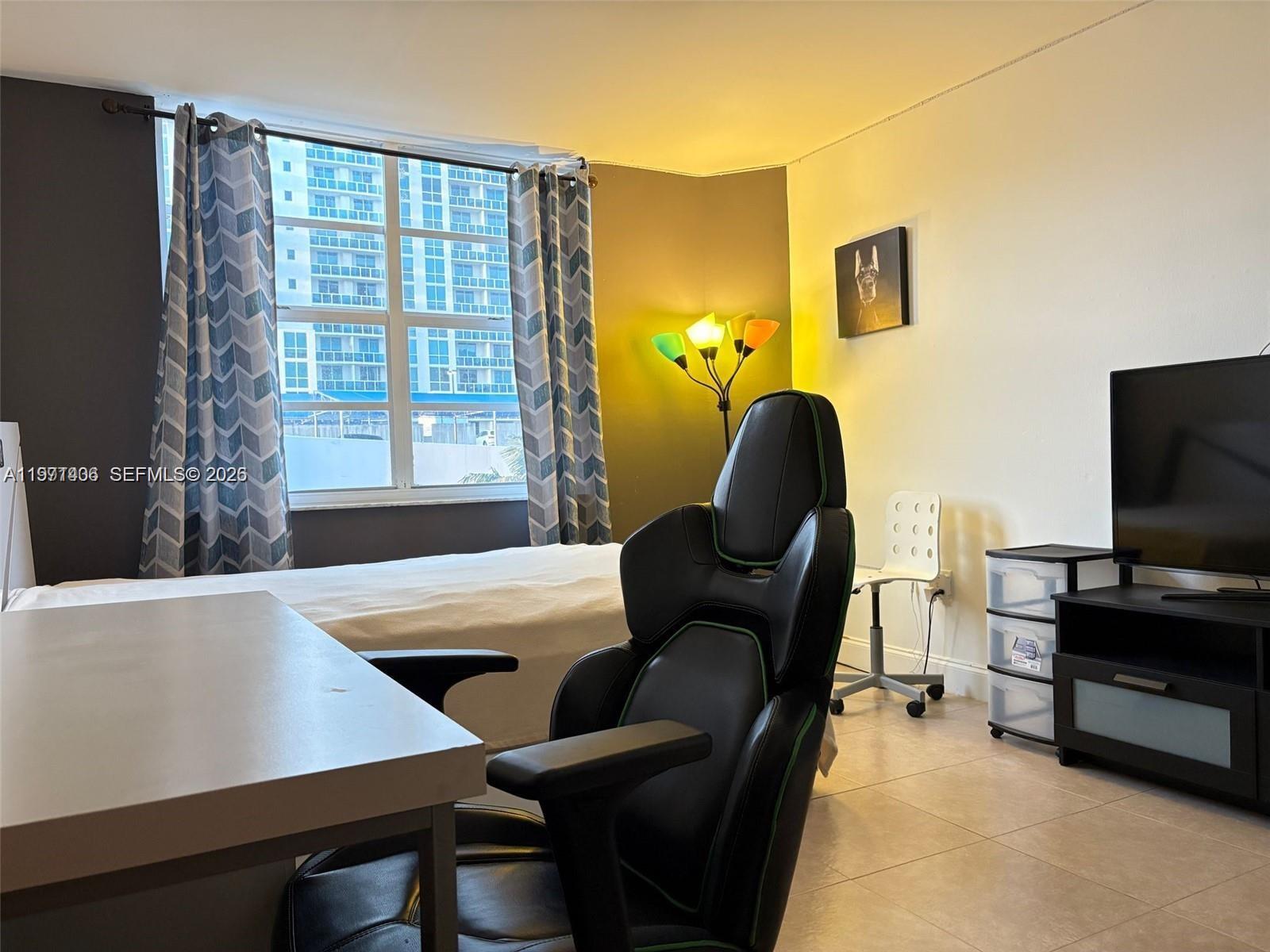 A bedroom features a gaming chair, a desk, a bed, and a window with city views — 1965 S Ocean Dr # 2F, Hallandale Beach FL 33009, HALLANDALE BEACH, FL