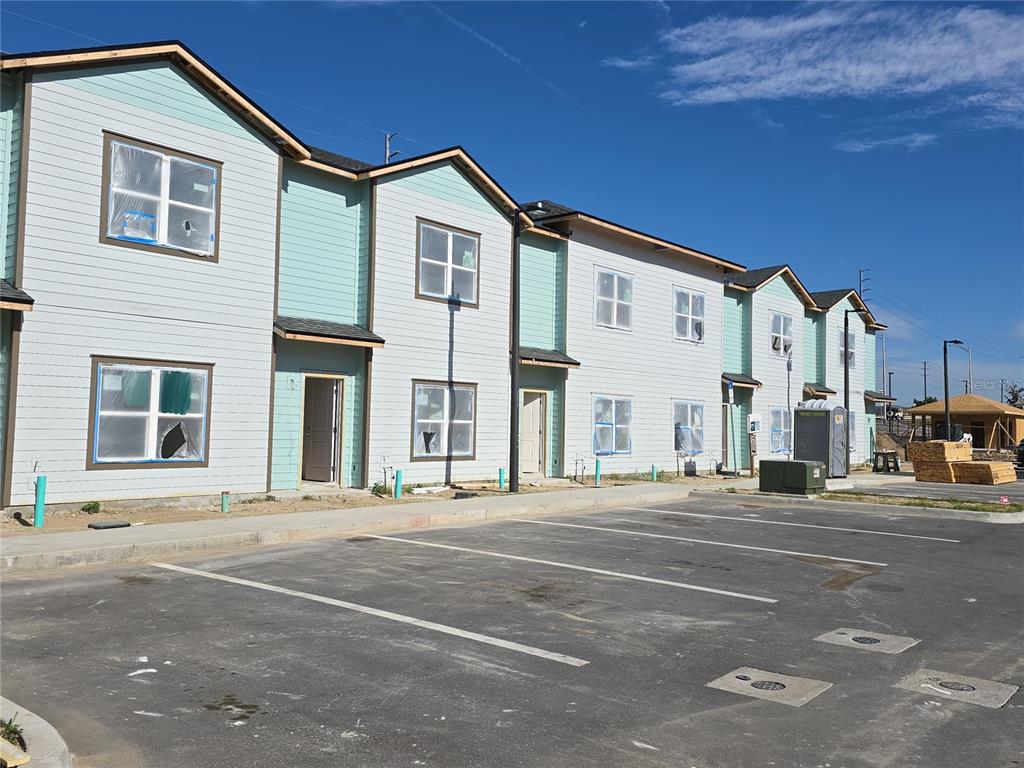 A row of newly constructed two-story townhomes with light-colored siding and a paved parking lot — 610 TULSA WAY UNIT 624, DAVENPORT, FL