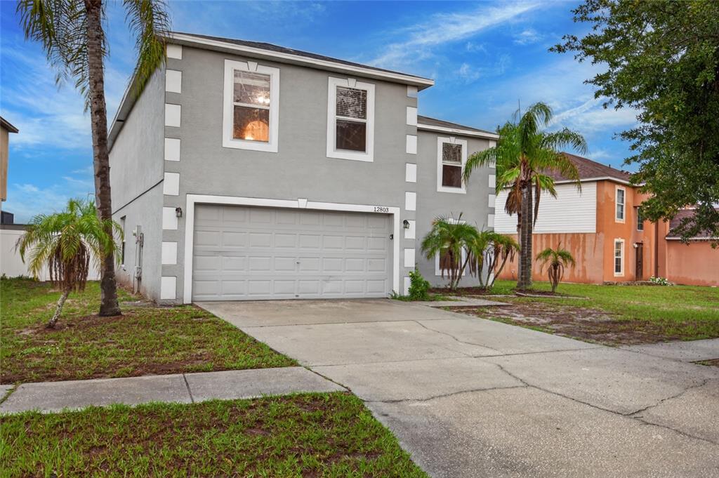 A two-story gray house with white corner accents and a two-car garage — 12803 LAKE VISTA DRIVE, GIBSONTON, FL