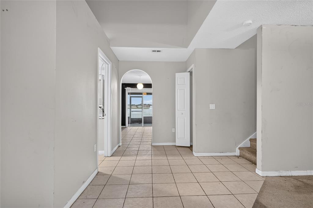 A tiled entryway leads to an arched doorway with a view of a screened patio — 12803 LAKE VISTA DRIVE, GIBSONTON, FL
