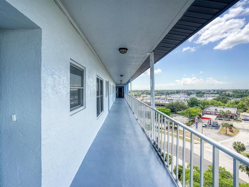 An outdoor apartment balcony with a metal railing overlooks a parking lot and street — 4939 FLORAMAR TERRACE UNIT 904, NEW PORT RICHEY, FL