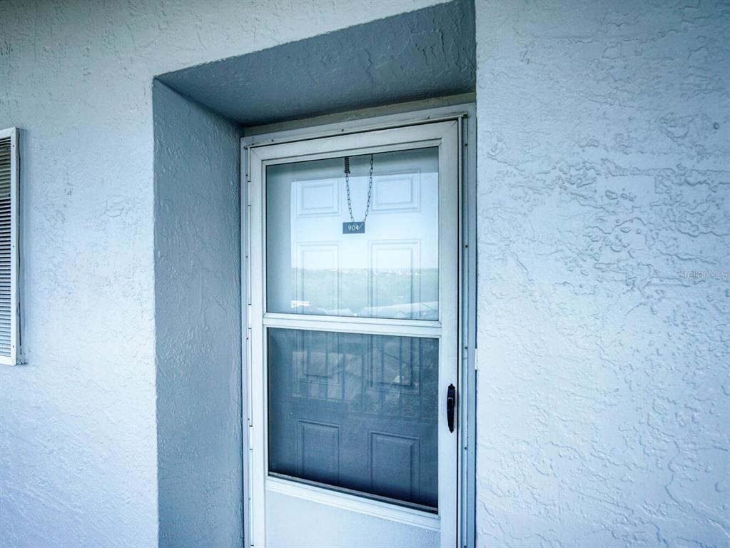 A white exterior door with a screen and a hanging number sign — 4939 FLORAMAR TERRACE UNIT 904, NEW PORT RICHEY, FL