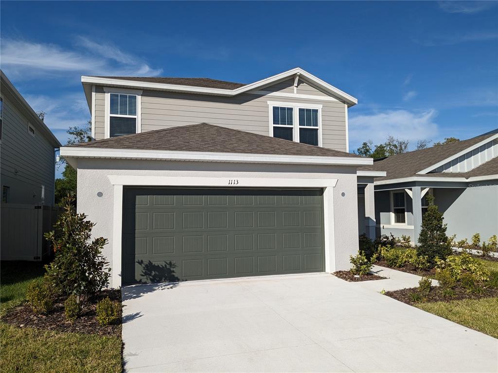 A two-story house with a gray garage door, light-colored stucco, and gray siding — 1113 GRAND HAMMOCK COURT, KISSIMMEE, FL