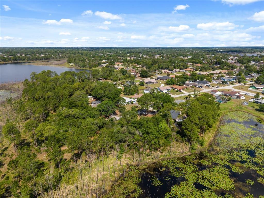 An aerial view shows a residential neighborhood surrounded by dense trees and two bodies of water — 1351 MELSHIRE AVENUE, DELTONA, FL