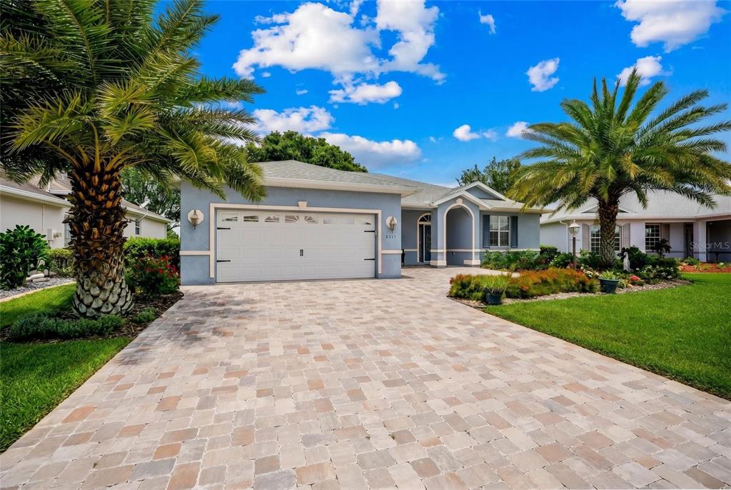 A blue single-story house with a paver driveway and two palm trees in the front — 8371 SW 84TH LOOP, OCALA, FL