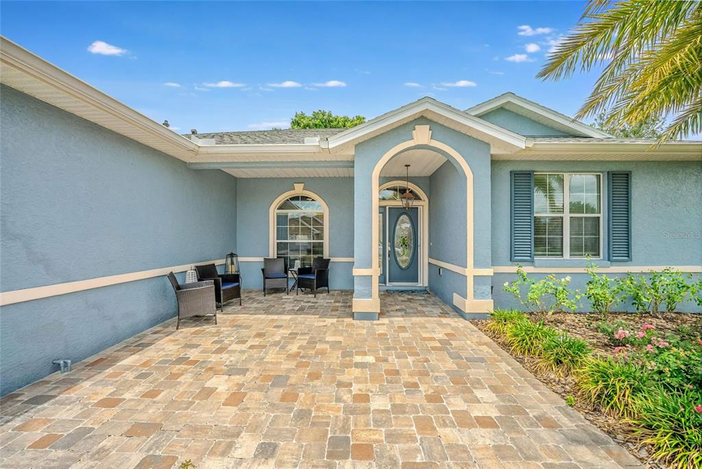 A blue house exterior features a stone-paved entryway, arched windows, and a covered front porch — 8371 SW 84TH LOOP, OCALA, FL