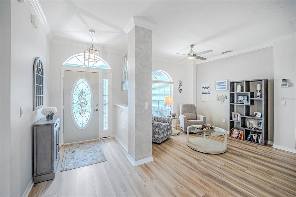 A bright entryway leads into a living area with wood-look flooring and a bookshelf — 8371 SW 84TH LOOP, OCALA, FL