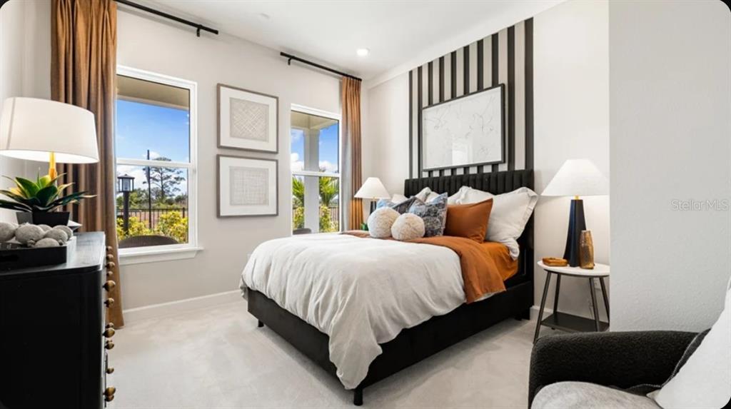 A bedroom features a black bed frame, striped accent wall, and two windows with curtains — 17742 SEDONA STREET, WINTER GARDEN, FL