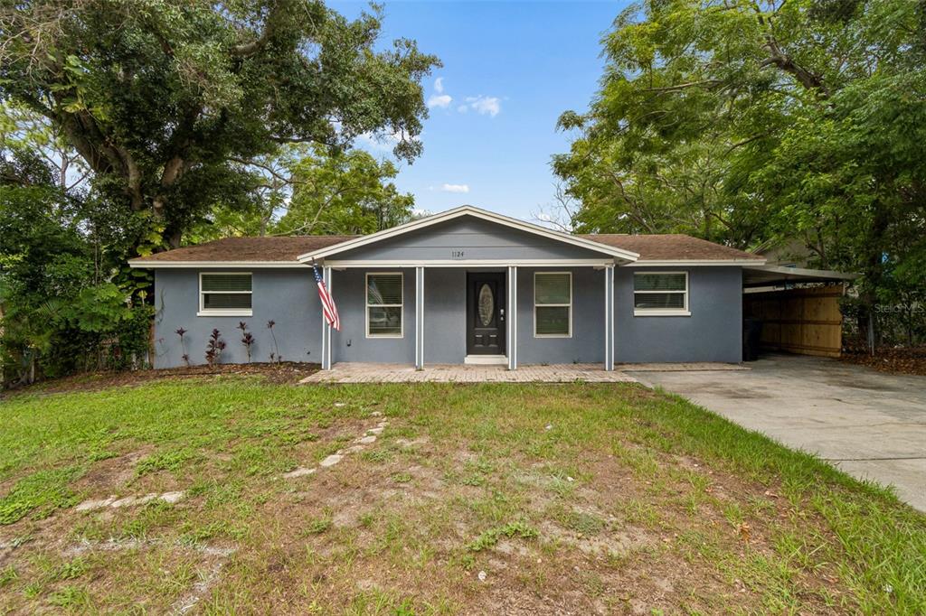 A single-story gray house with a front porch, a concrete driveway, and mature trees — 1124 JADEWOOD AVENUE, CLEARWATER, FL
