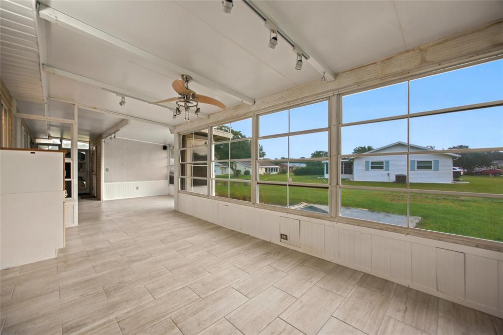 An empty bedroom with wood-look flooring, a ceiling fan, a window, and white closet doors — 6483 SW 110TH STREET, OCALA, FL