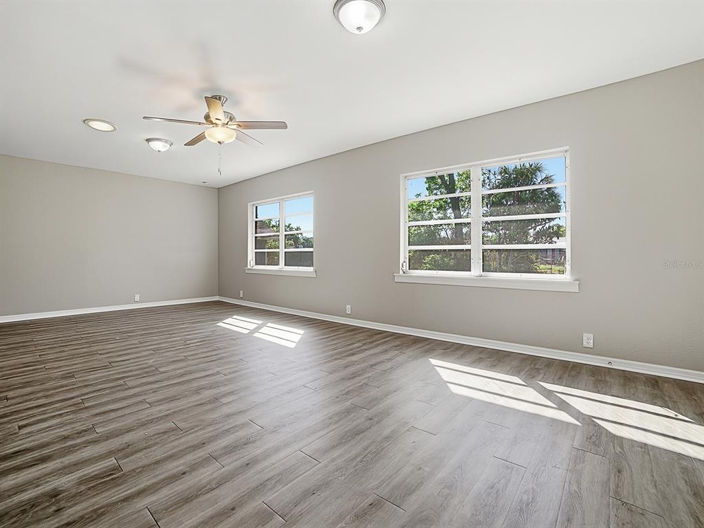 An empty room with gray walls, wood-look flooring, a ceiling fan, and two windows — 5 OAK STREET, YALAHA, FL