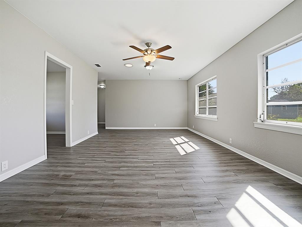An empty room features gray wood-look flooring, light gray walls, and a ceiling fan — 5 OAK STREET, YALAHA, FL